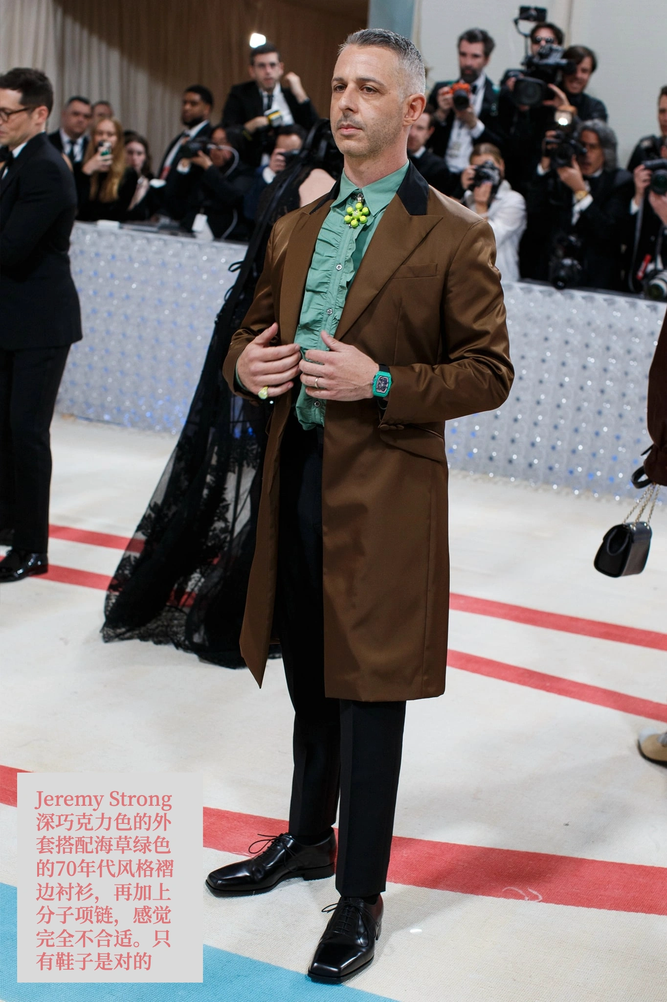 Jeremy Strong。这件深巧克力色的外套搭配海草绿色的70年代风格褶边衬衫，再加上分子项链，感觉完全不合适。只有鞋子是对的。